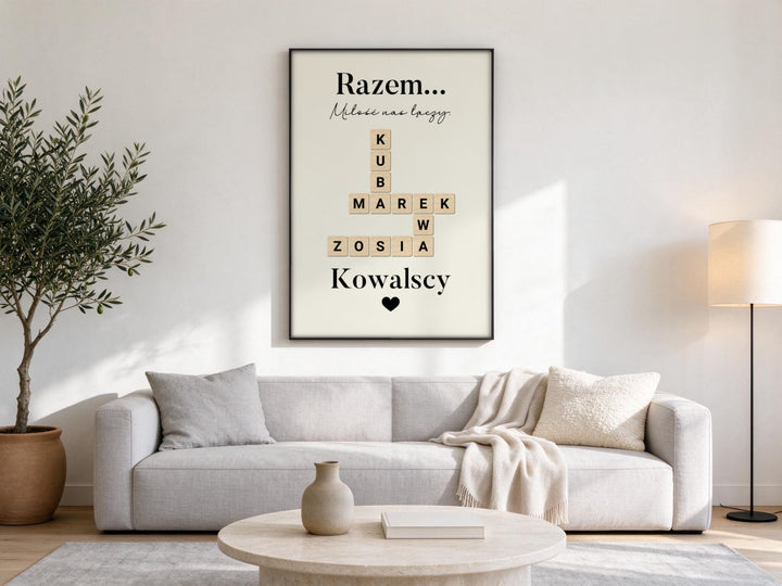 Dekoracje ścienne do salonu: plakat Razem… z imionami rodziny w czarnej ramie nad jasnoszarą kanapą